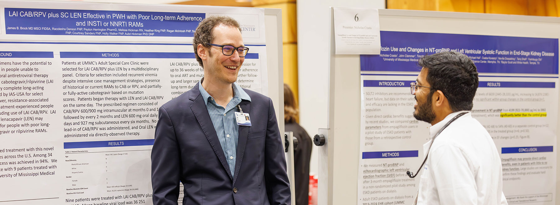 Two researchers discuss findings in front of large scientific research posters. Two researchers discuss findings in front of large scientific research posters.
